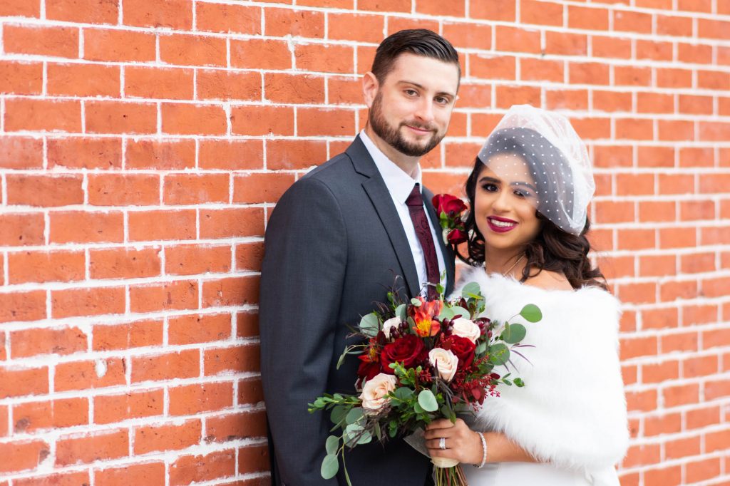 bride and groom on brick wall