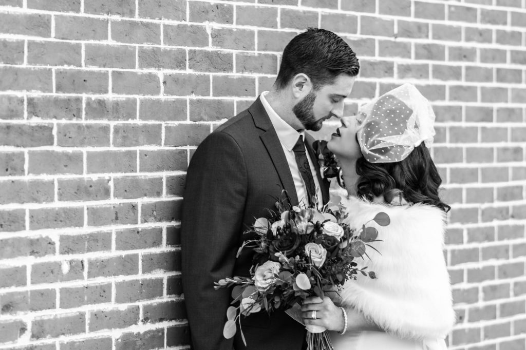 bride and groom against brick wall
